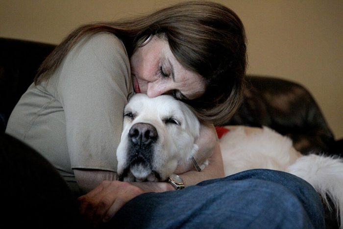 Woman cuddling with her dog on a couch