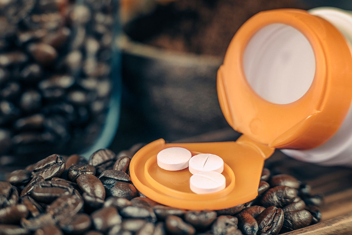 Caffeine supplementation bottle with pills and roasted coffee beans on a wooden plate 