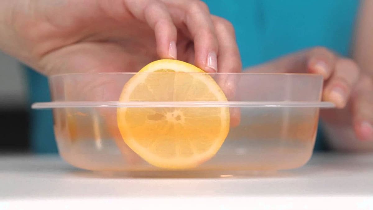 Holding a lemon in a plastic container 