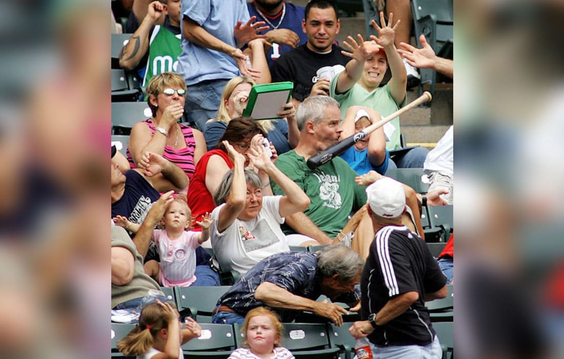 A man in the bleachers with a baseball bat about to him 