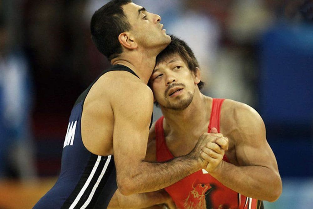 Two wrestlers holding hands in a match 