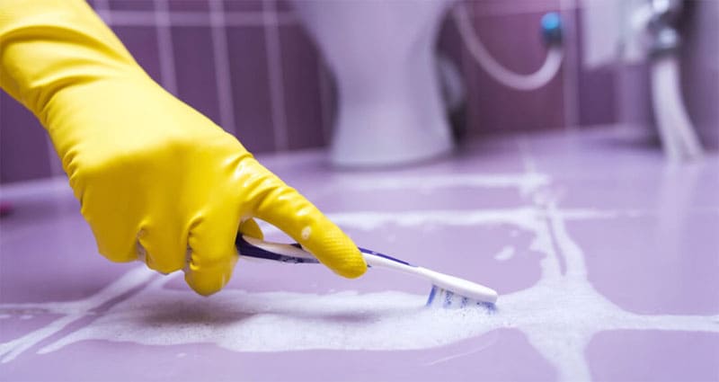 bathroom floor being cleaned with a toothbrush