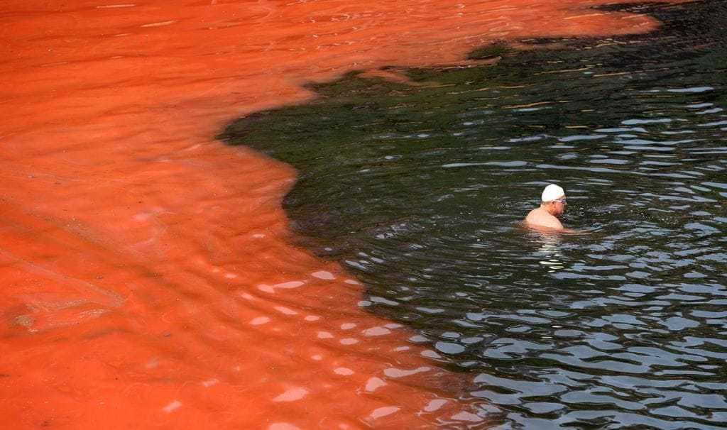 man swimming in red and black water
