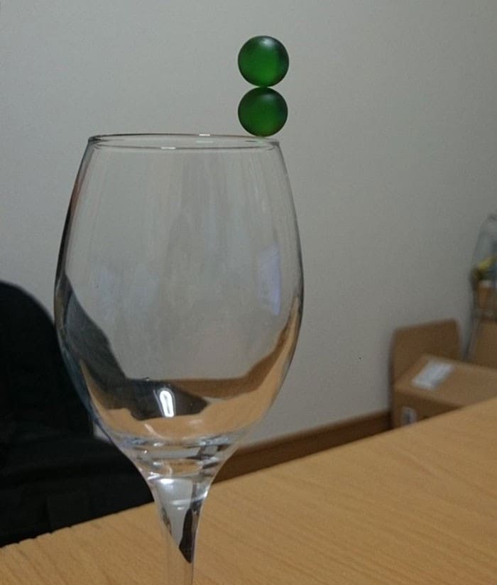 Two marbles balancing on top of a wine glass