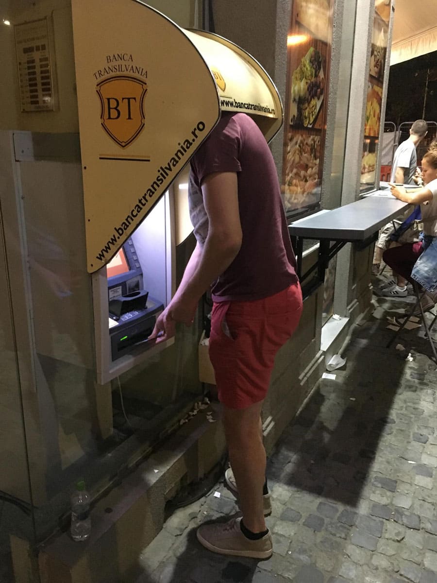 A man standing at an ATM with the shelter over him