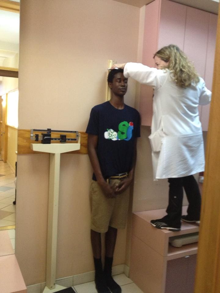A man in a doctor’s room having his height calculated