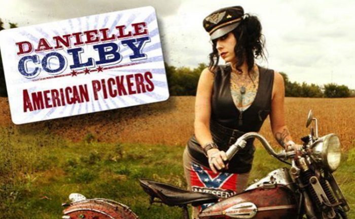 Danielle standing next to a bike with a sign for ‘Danielle Colby: American Pickers’