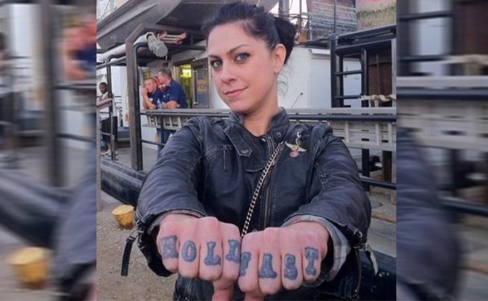 Danielle Colby holding out her knuckles with a tattoo on them 