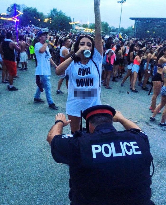 A cop bowing down in front of a girl at a music festival 