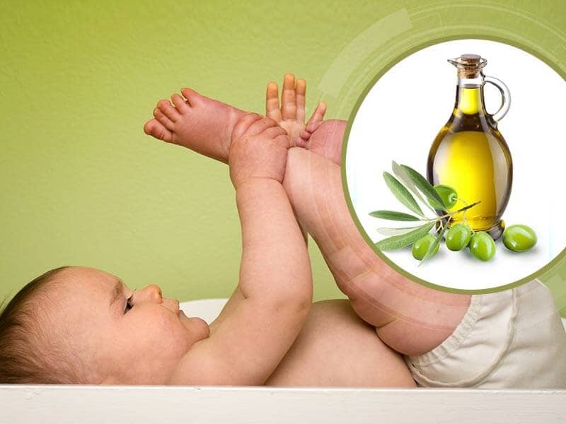 A baby in a diaper with a bottle of olive oil. 