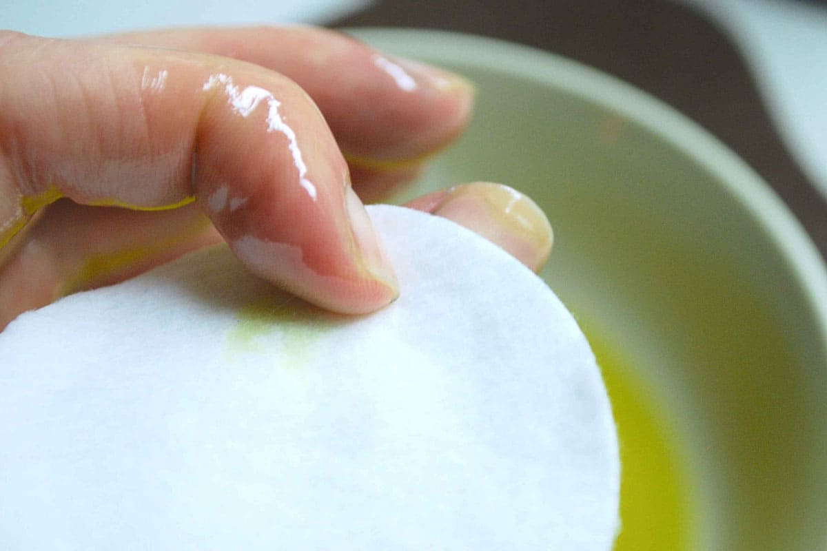 A bowl of olive oil used to moisturize a woman's hand and nails. 