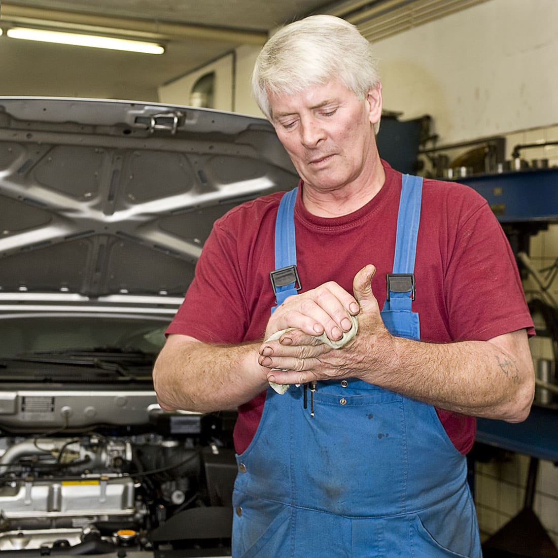 A motor mechanic cleaning his greasy hands after servicing a car.
