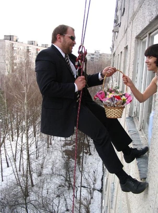 groom giving bride flowers on the side of a building 