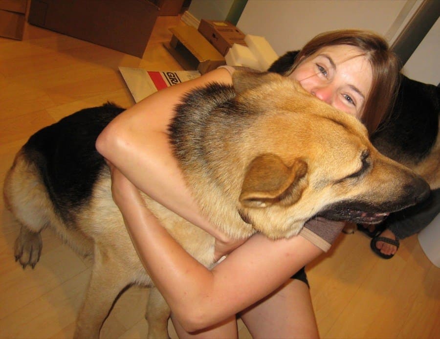 Photograph of a woman hugging a German Shepard dog. 