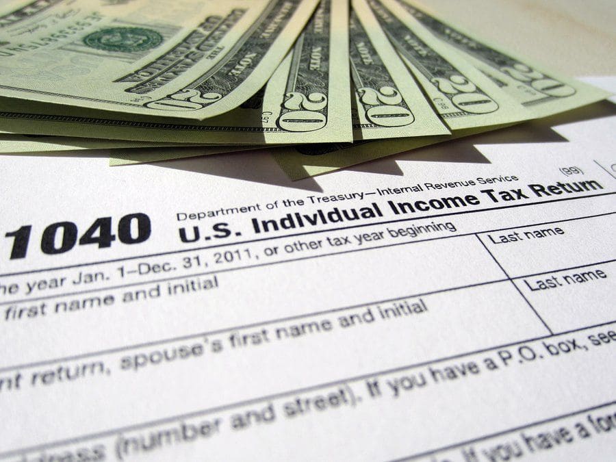 Photograph of a 1040 U.S. Individual Income Tax Return form along with five $20 bills. 
