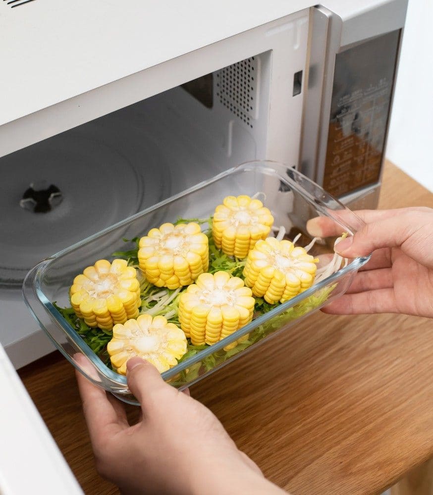 A person carryng corn to the microwave.