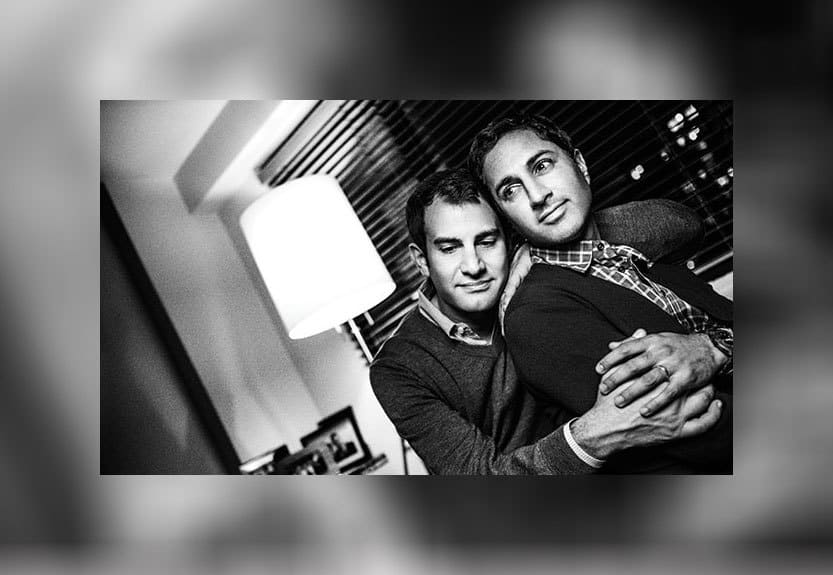 Maulik Pancholy and Ryan Corvaia embracing in a black and white photograph.