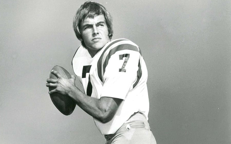 Black and white photograph of Mark Harmon in a football uniform about to toss one around.