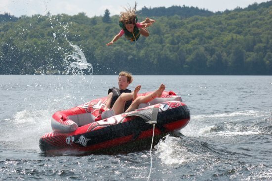 People tubing on a lake and one of the girls is flying in the air