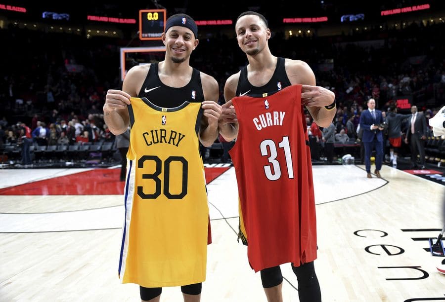Steph and Seth Curry holding up their jerseys with the numbers 30 and 31.