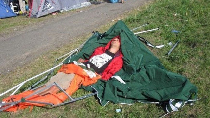 Man lying in collapsed tent on the ground 