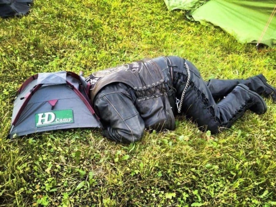 Man lying on the ground with his head on a mini tent 