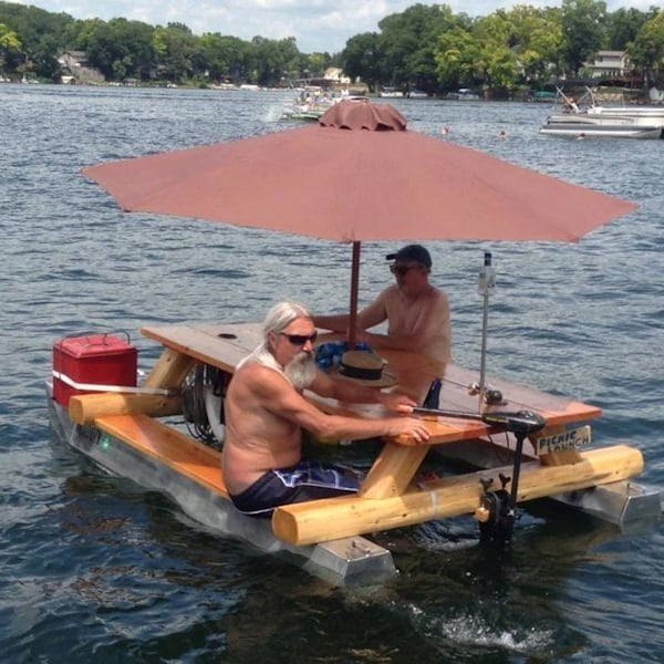 two men sitting on a picnic table-turned boat 