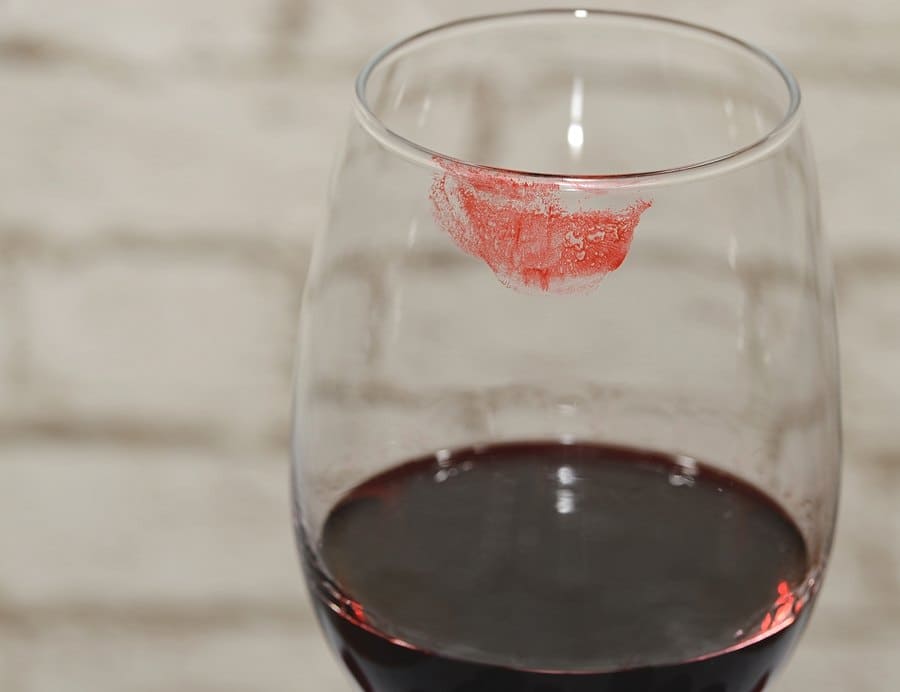 A wine glass with a red lipstick mark. 
