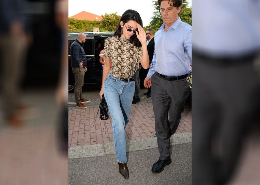 Kendall Jenner is wearing a snakeskin short-sleeved shirt and jeans. 
