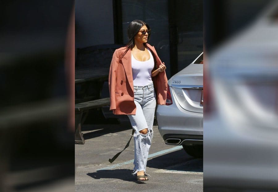 Kourtney Kardashian out and about in light jeans, a white tank top, and a salmon-colored blazer. 