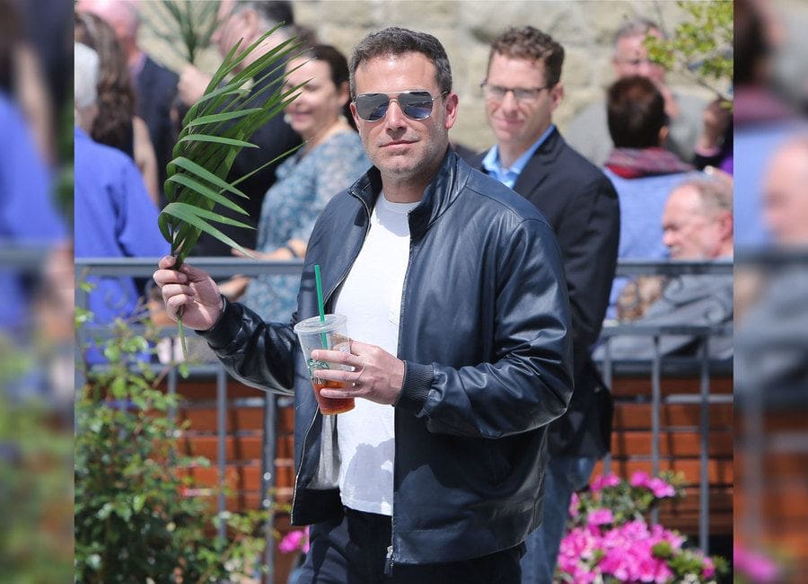 Ben Affleck out and about holding his iced coffee from Starbucks and a branch of leaves in his other hand. 