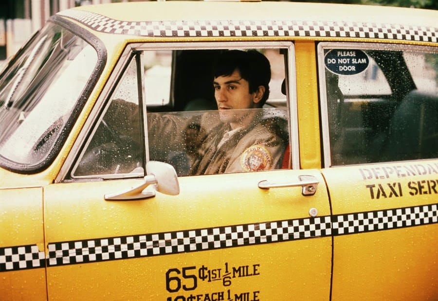 Robert De Niro in Taxi Driver, driving a taxi. 