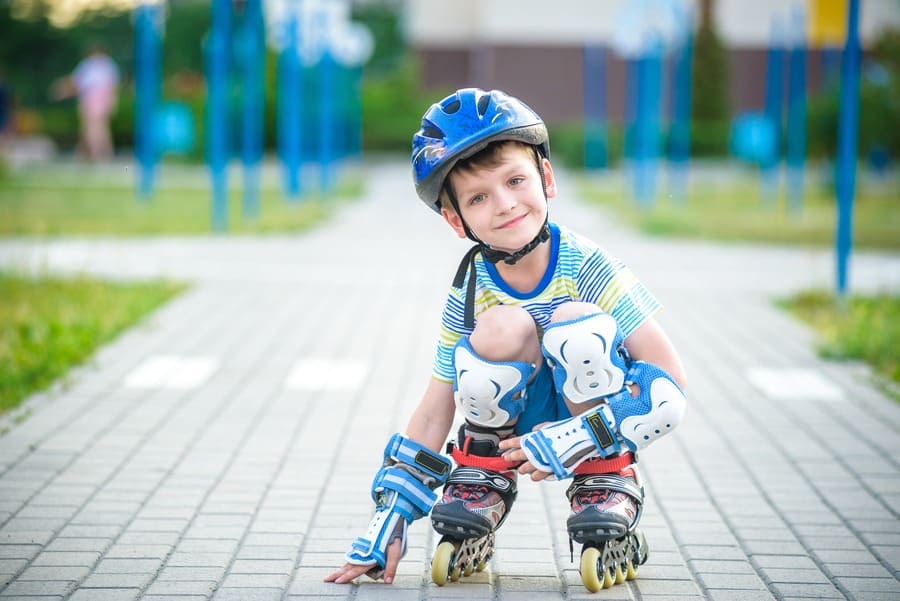 Smiling boy with inline skates and protective gear