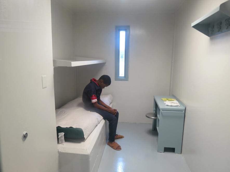 Boy sitting in a juvenile detention cell