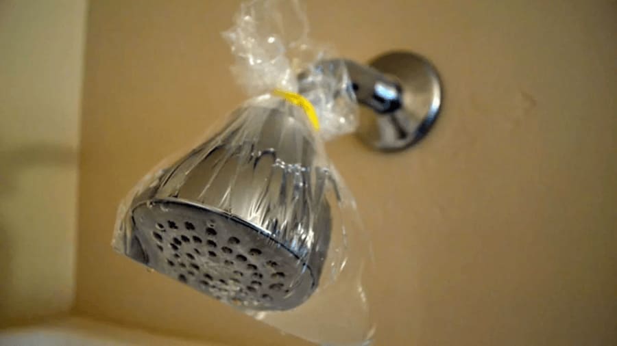A showerhead with a plastic bag filled with vinegar tied around it. 