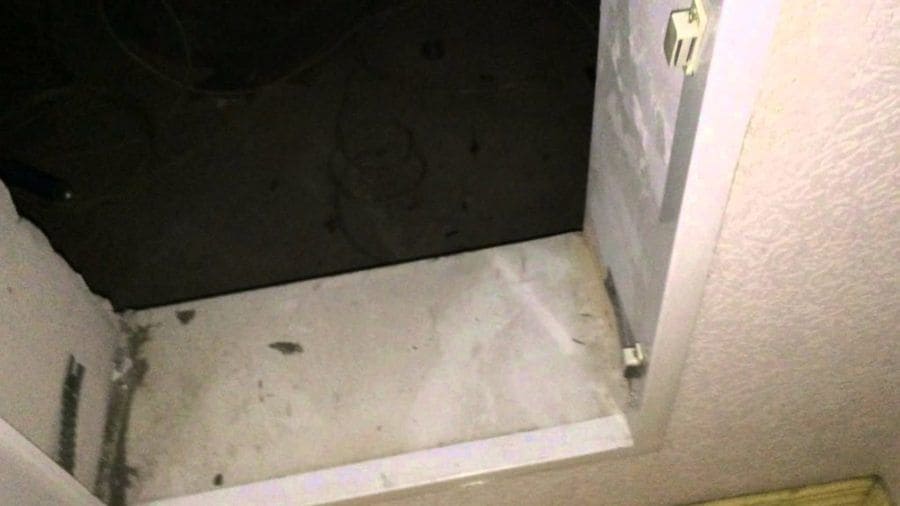 The mysterious door being opened with a dark view of the floor directly inside. 