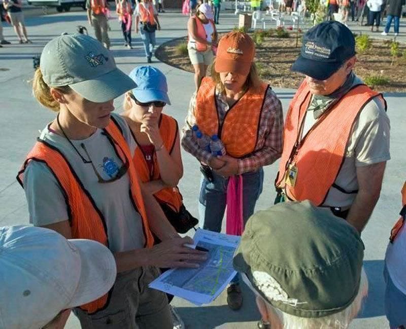 A photograph people in orange vests studying a map and ready to go look for Paige 