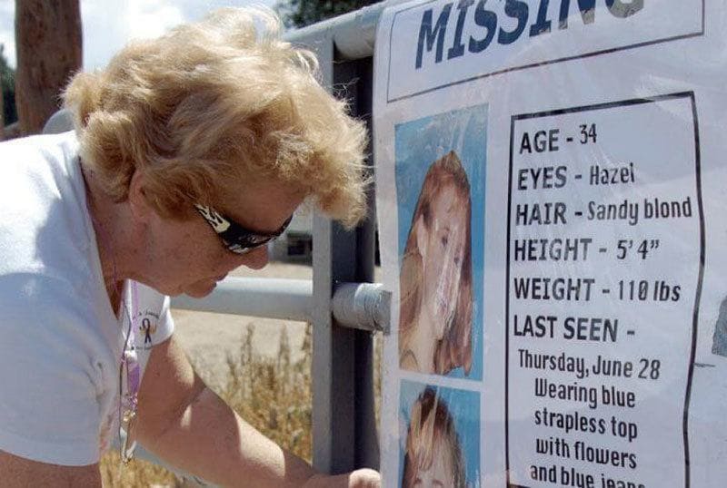 A volunteer is hanging a missing person poster for Paige 