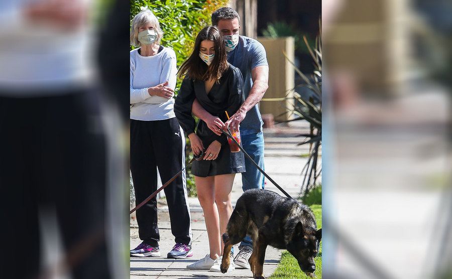 Ben Affleck and Ana De Armas tangled up, both holding their dogs on a leash 