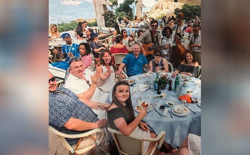 Wiz Khalifa at the table next to a family, who are taking a family photograph together 