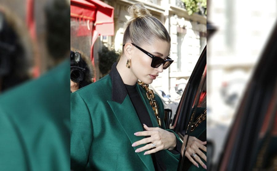 Hailey Bieber in an emerald green jacket with her oval-shaped ring showing 