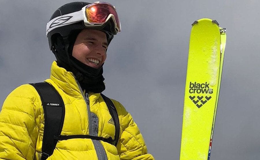 Matt Moniz holding florescent yellow skiis which match his jacket 