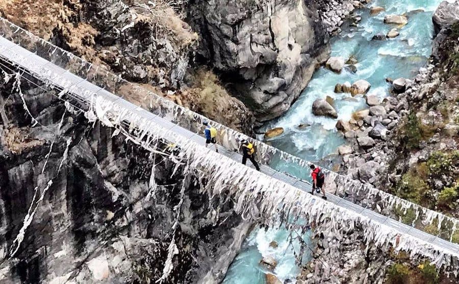 Matt Moniz and hikers crossing a long bridge over water 