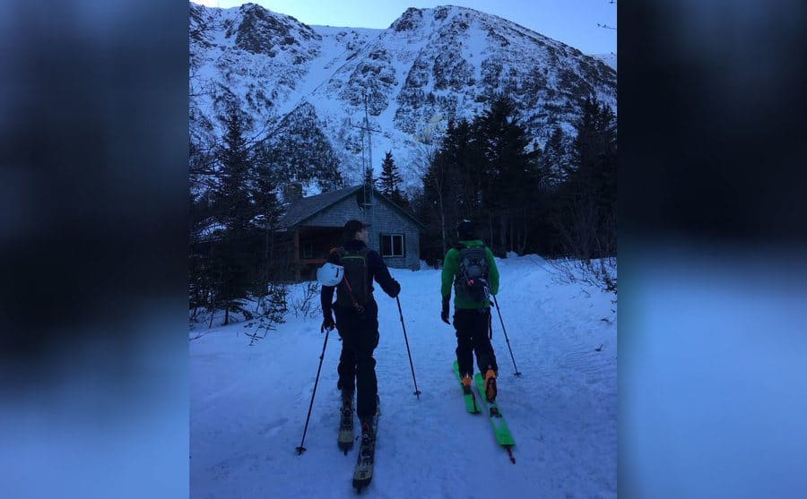 Matt and a friend cross country skiing towards a cabin 