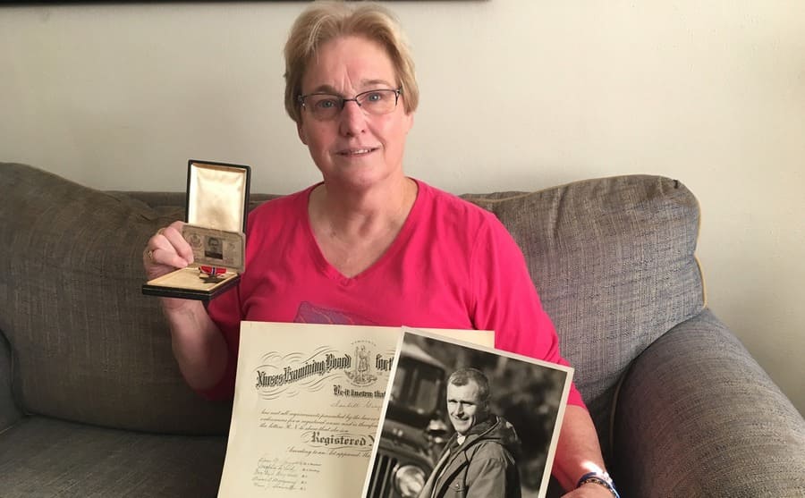Their daughter Laura holding up his od photograph and his World War II memorabilia 