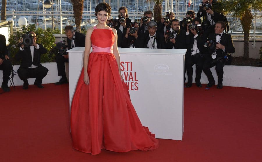 Audrey Tautou wearing a red pleated dress with pink fabric crossed across her stomach and pink straps
