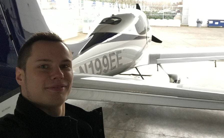 A photograph of Colton in front of a plane 