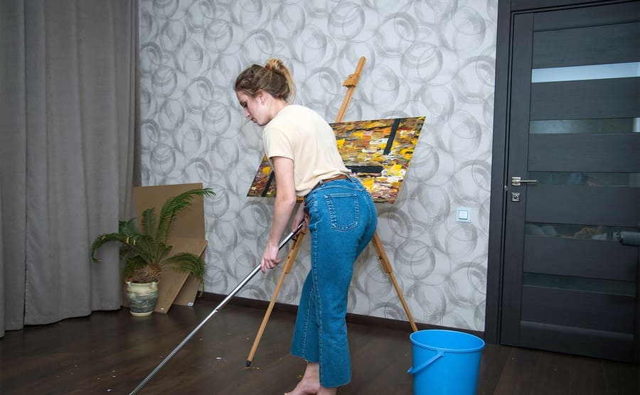 A teenage girl cleaning wooden floors in a nice home 