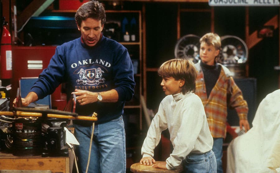 Tim Allen showing his on screen sons how to do something in the garage 