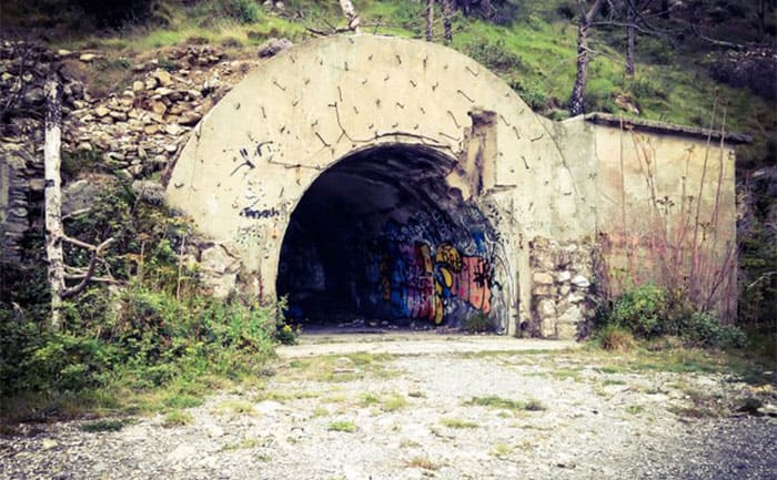 The Monte Moro bunker entrance hidden in the side of a hill with graffiti painted inside 